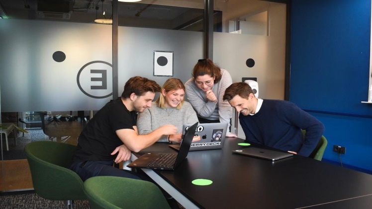 Four people smiling and looking at a laptop screen using bubble plots to improve decision-making.